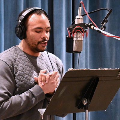 Josh Griffin, wearing headphones, standing at a microphone.