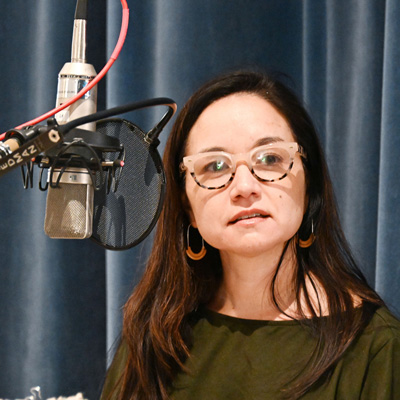 Mary Pan next to a microphone, looking toward the camera.